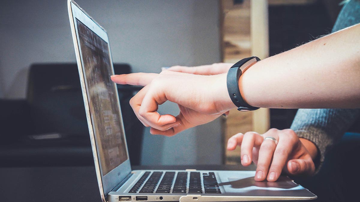 Person pointing at laptop screen while reviewing LMS compliance features